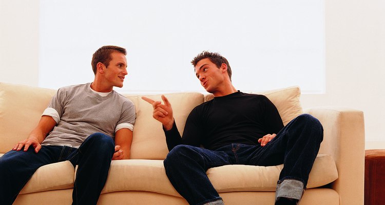Dos hombres conversando en un sillón.