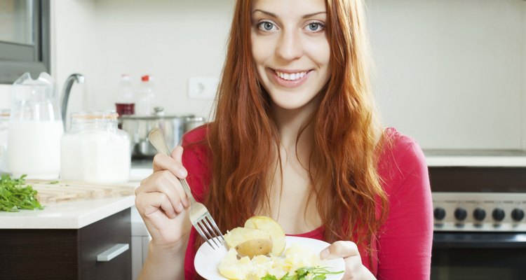 positive girl in red eating jacket potatoes