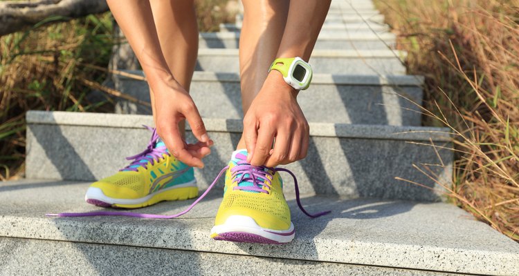 young woman runner tying shoelaces on stone trail