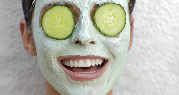 Woman with facial mask and cucumbers over eyes