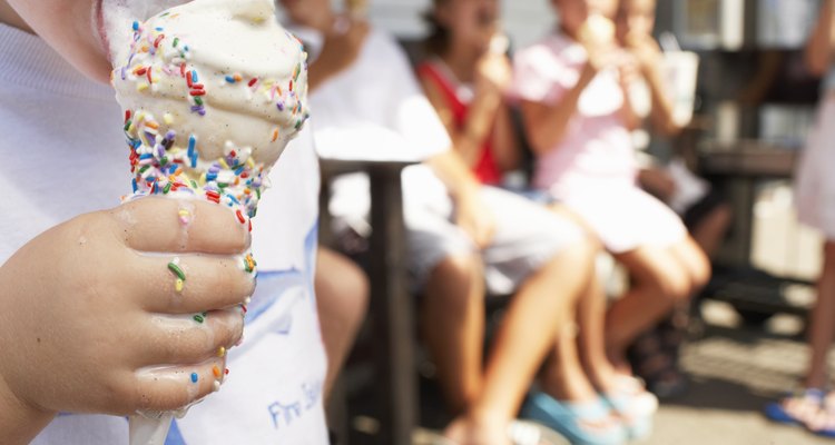 Boy (2-4) licking ice cream, close-up, other children in background