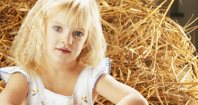 Girl (4-5) sitting by haystack, portrait