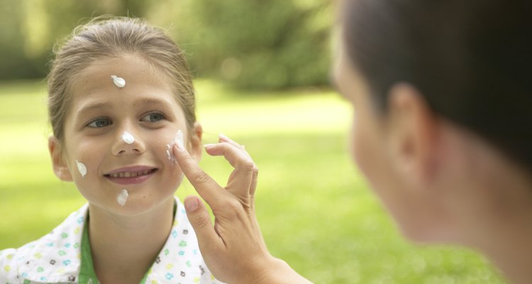 Mother applying sun lotion to daughter's (7-9) face, outdoors