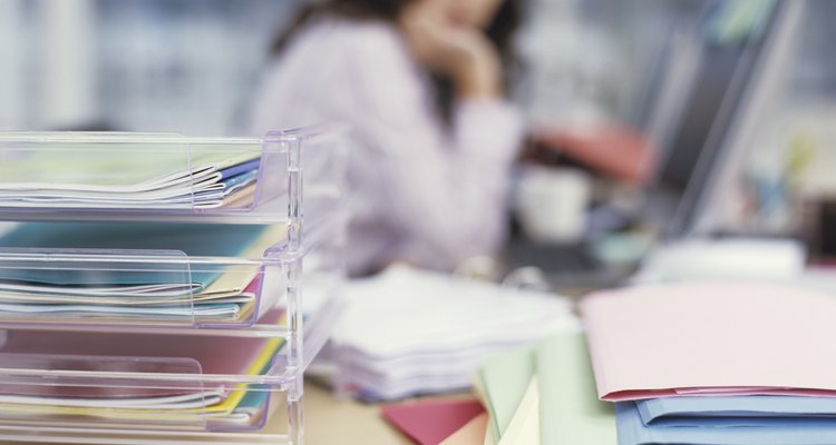 Woman sitting at desk, files and in and out trays, close up