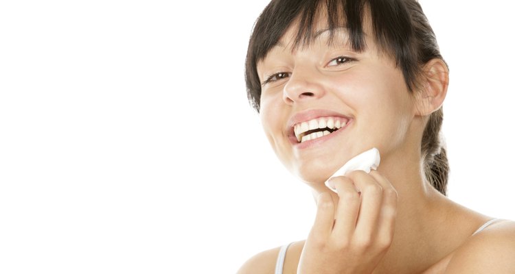 Young woman removing makeup with cleansing pad