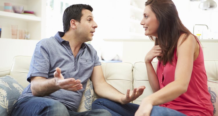 Hispanic Couple Sitting On Sofa Arguing