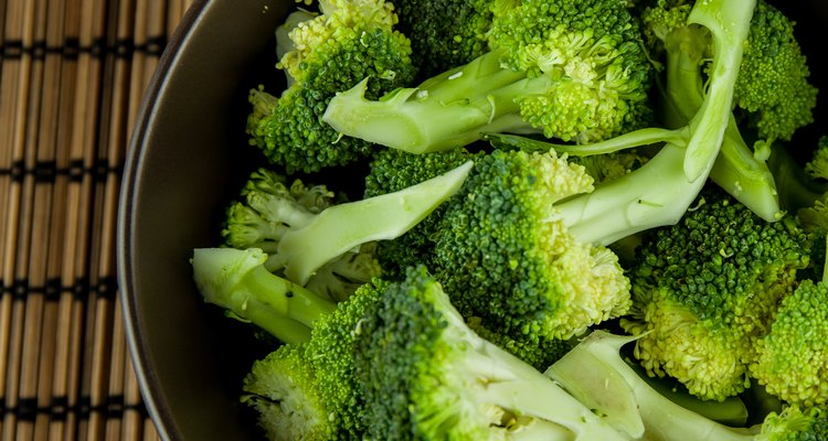 Bunch of fresh green broccoli in bowl over wooden background