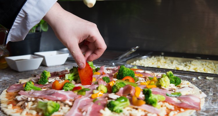 Chef prepares pizza with vegetables
