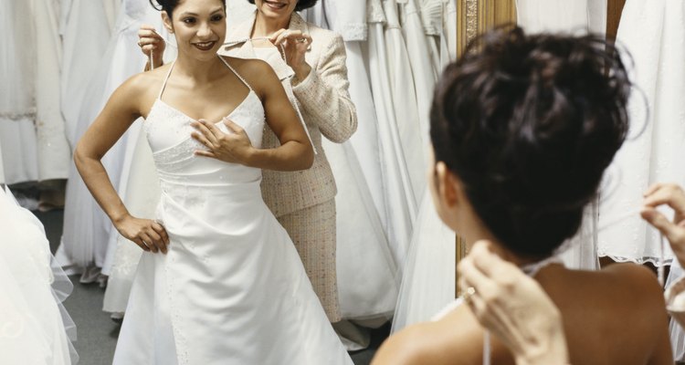 Senior Woman Helping Her Daughter Try on a Wedding Dress in Front of a Mirror in a Bridal Shop