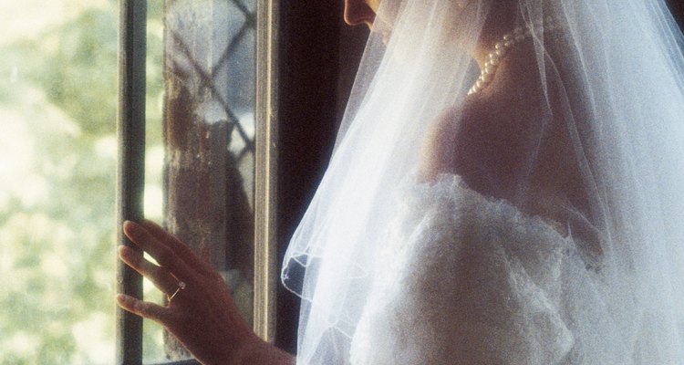 Woman in wedding gown looking out window of church