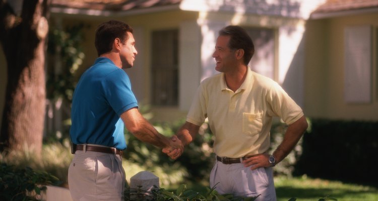 Two men shaking hands over fence