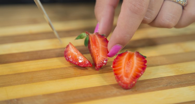 Unrecognizable woman cutting strawberry.