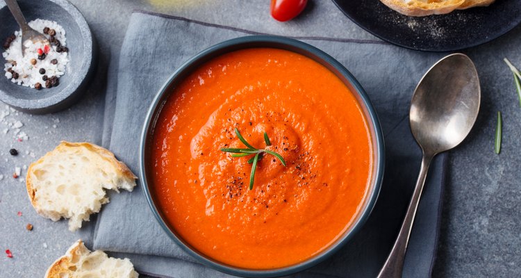 Tomato soup in a black bowl on grey stone background. Top view. Copy space.