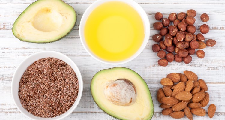 Foods with healthy fats. Sources of omega 3 - avocado, olive oil, nuts and flax seed on wooden background. Healthy food concept. Top view