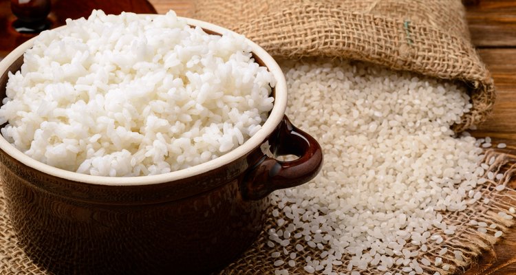 Boiled white rice in ceramic pot on wooden background.