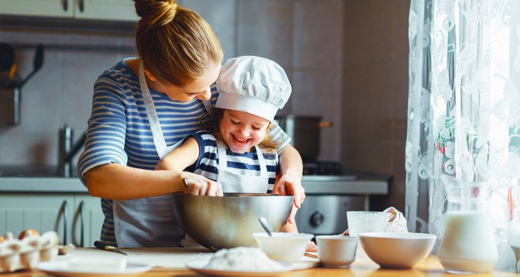 happy family in kitchen. mother and child preparing batter, bake cake