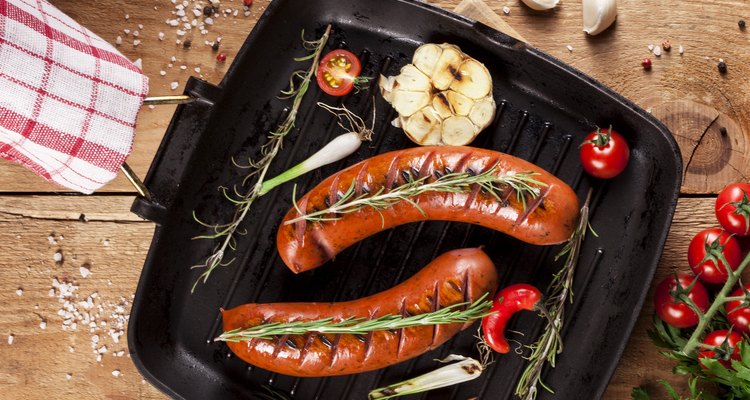 Grilled sausages in a pan on wooden background