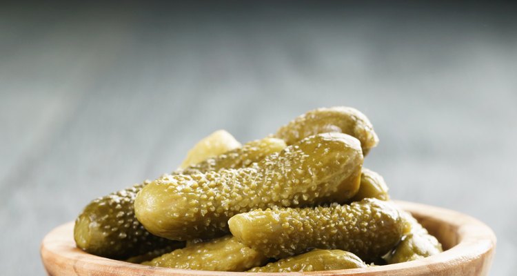 marinated cornichons in wooden bowl