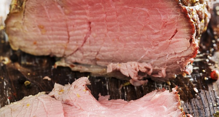 Cuts of warm, pink roast beef on a wooden surface