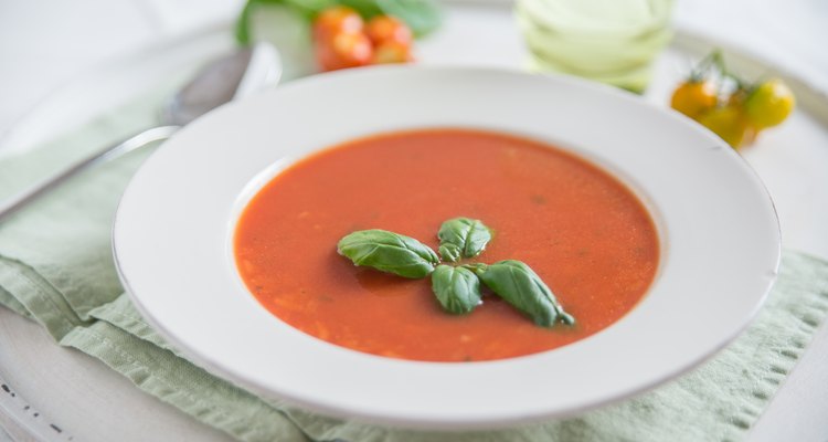A bowl of fresh cream of tomato soup garnished with basil leaves