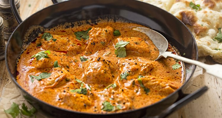 Homemade butter chicken in a serving dish with naan bread
