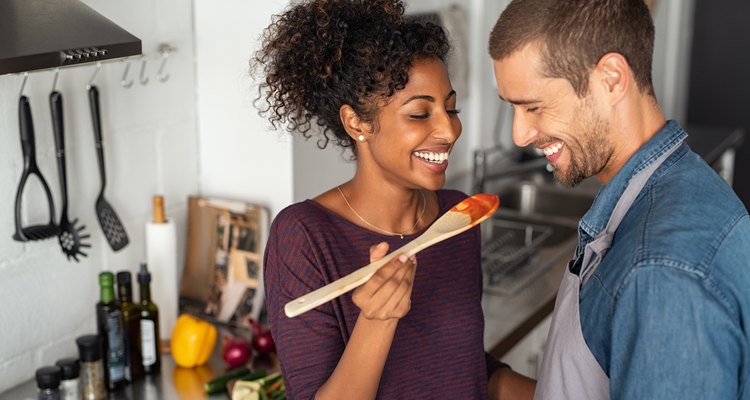 Multiethnic couple tasting food from wooden spoon
