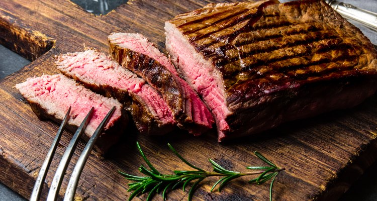 Sliced grilled medium rare beef steak served on wooden board Barbecue, bbq meat beef tenderloin. Top view, slate background