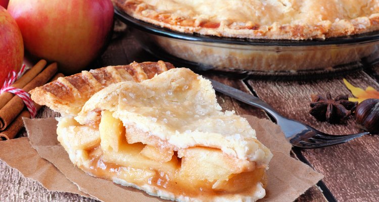 Slice of apple pie on paper on wooden table