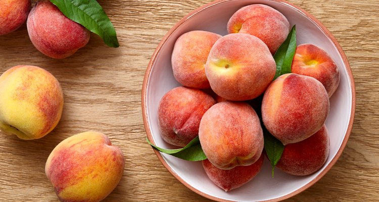 Ripe peaches in a bowl on wooden background