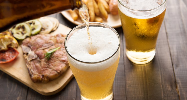 Beer being poured into glass with steak and french fries
