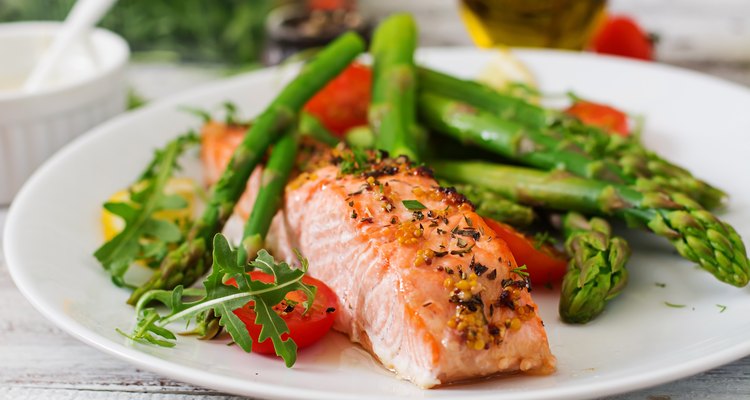 Baked salmon garnished with asparagus and tomatoes with herbs