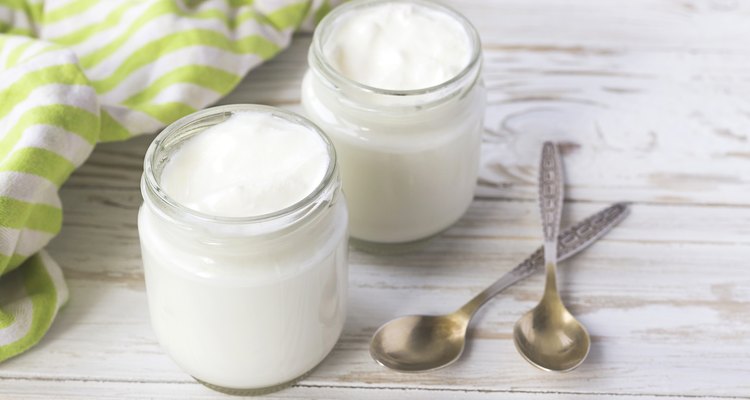 Homemade yogurt in glass jar on wooden table.