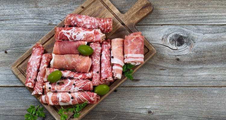 Various raw meats on rustic serving board