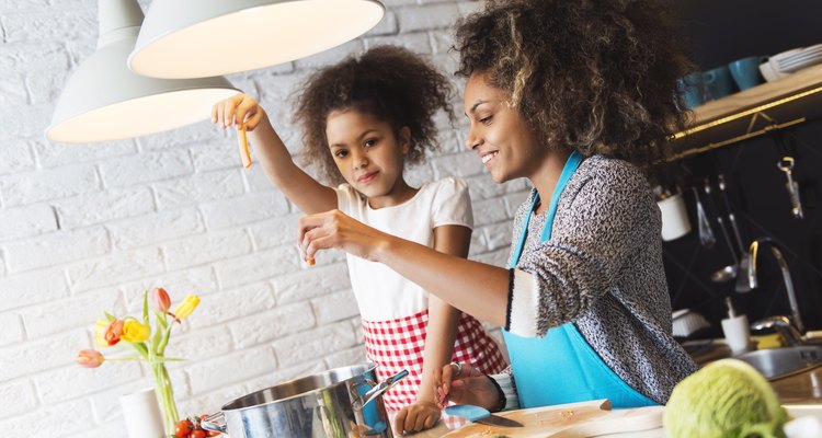 Beautiful African American woman and her daughter cooking in the kitchen