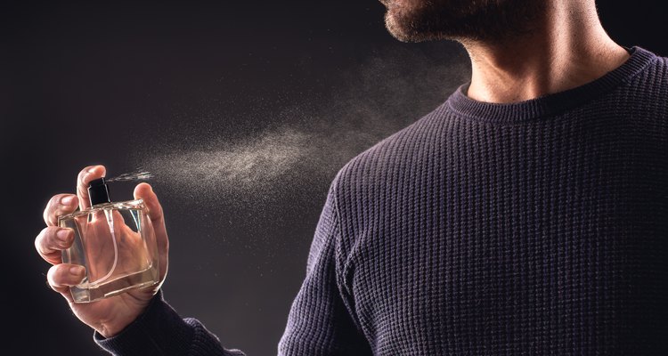 Man Spaying Perfume on Dark Background