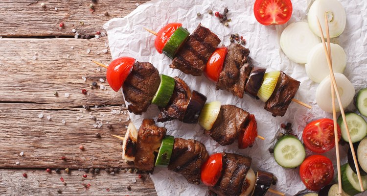 Tasty kebab with vegetables on skewers close-up. horizontal top view