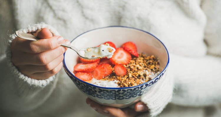 Healthy breakfast yogurt, granola, strawberry bowl in woman's hands