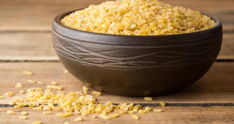 Wheat in ceramic bowl on rustic wooden background