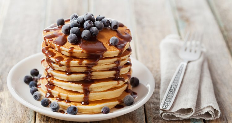 Pancakes with blueberry syrup on a plate on a wooden table