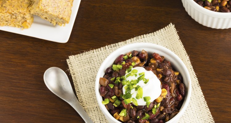 Black bean soup in a white bowl with spoon on a table