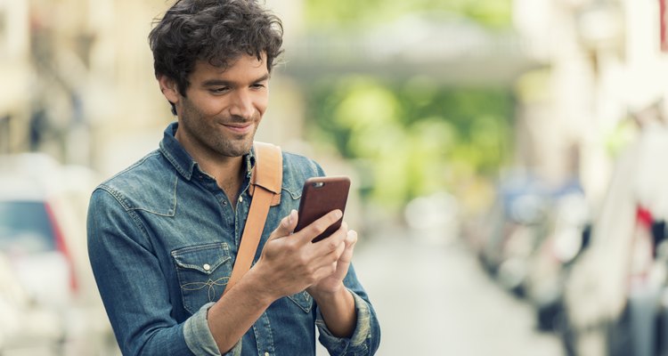 Cheerful male in the street texting on Mobile phone.