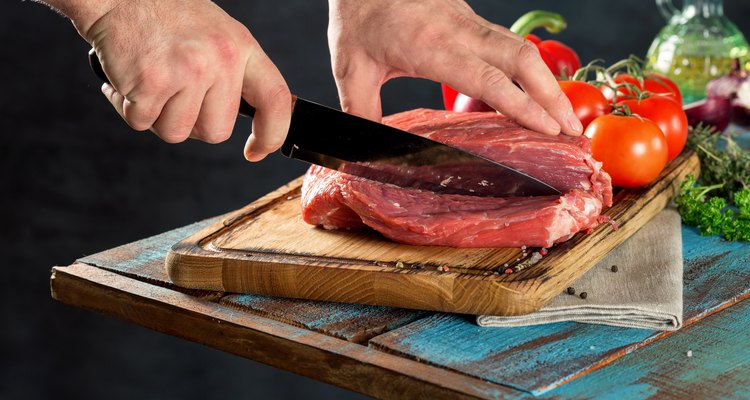 Butcher cutting beef meat on a wooden table