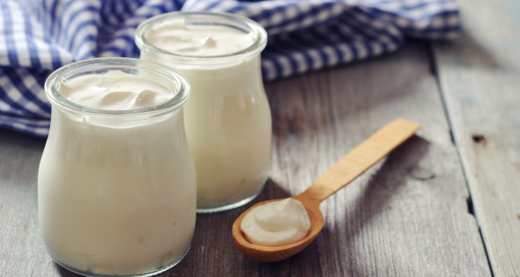 Greek yogurt in glass jars with wooden spoon on wood table