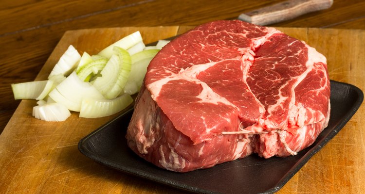 A slab of beef and onions on a baking tray