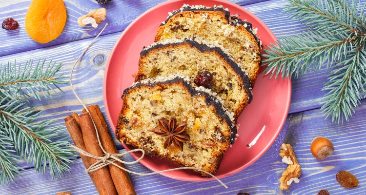 Fresh baked fruitcake for Christmas on plate and spruce branches on boards