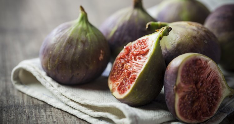 Whole and sliced figs on a folded linen on wood table