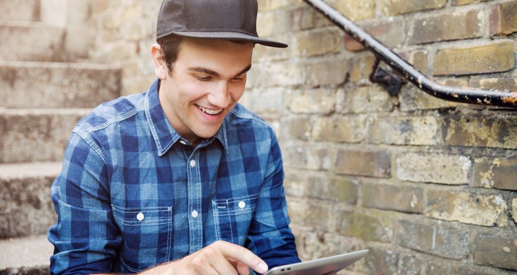 Young man sat on steps with tablet.