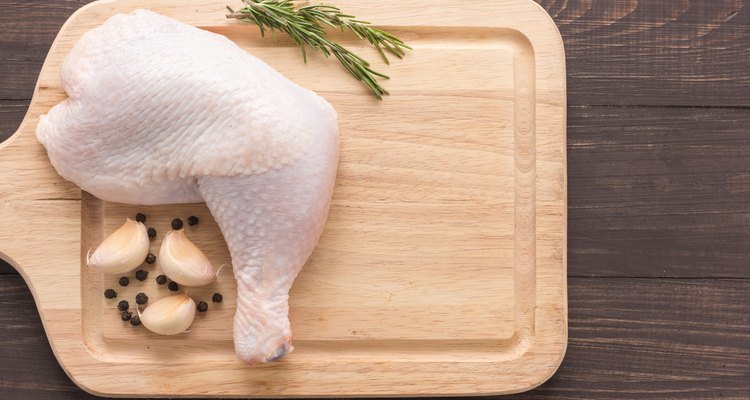 Raw chicken leg on cutting board on wooden background