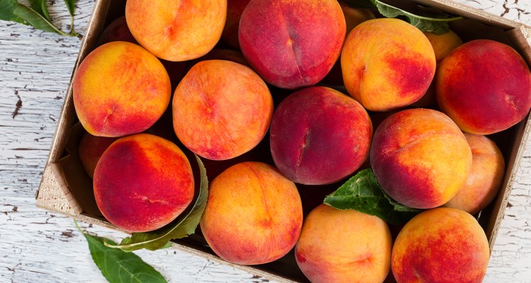 Fresh organic peaches in wooden crate viewed from above