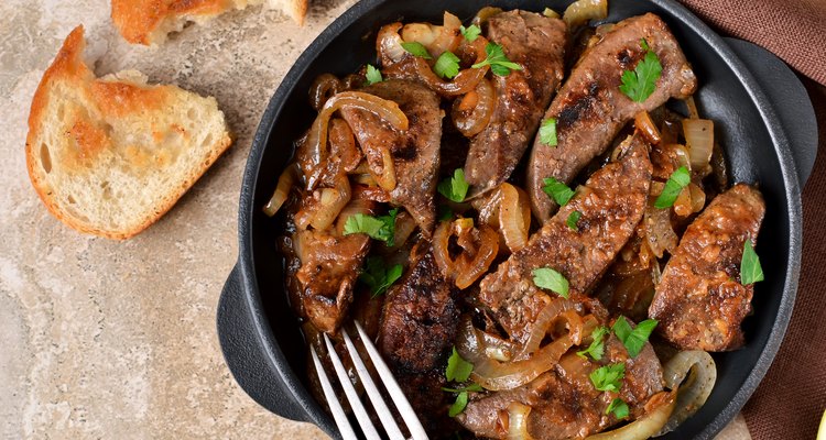 Fried liver with onions and apples on a concrete background